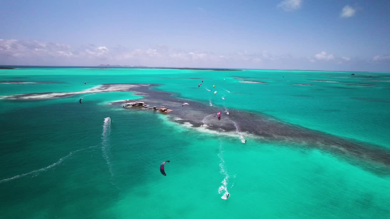 Kitesurfers glide across the turquoise waters of Los Roques, captured from an aerial perspective