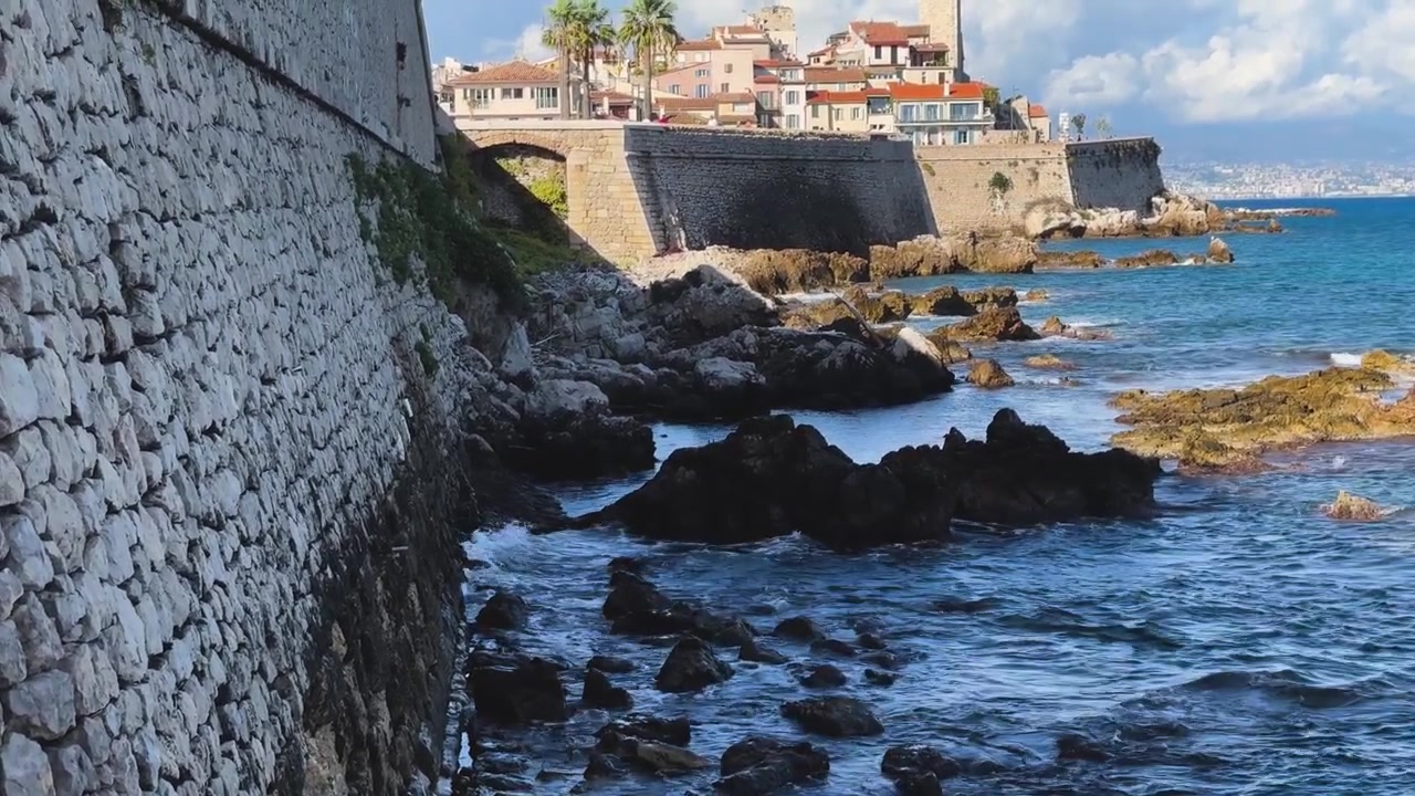 Antichi bastioni in pietra costeggiano la costa rocciosa mediterranea sotto il centro storico di Antibes in una giornata luminosa lungo la Costa Azzurra.