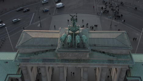 AERIAL:-Epic-close-up-view-of-Brandenburg-Gate-in-beautiful-sunset-light-revealing-car-traffic-in-background