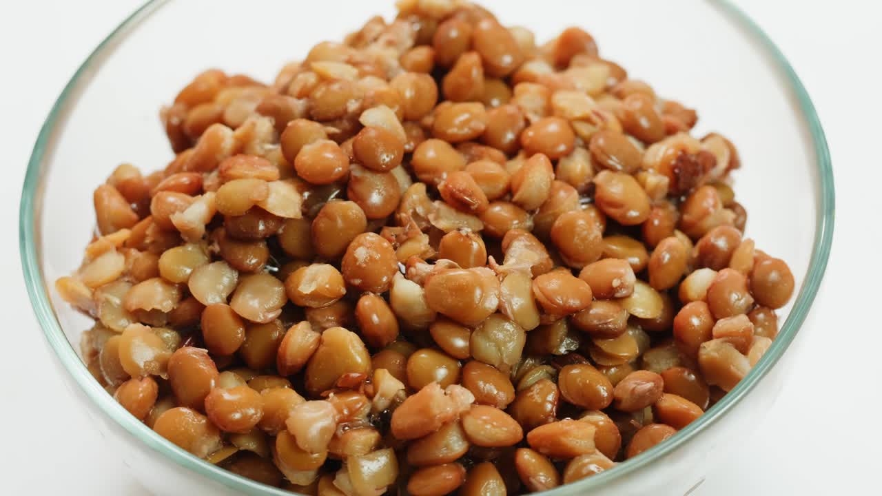 Lentils macro, Open metal can with preserved steamed brown lentils close up isolated on white background