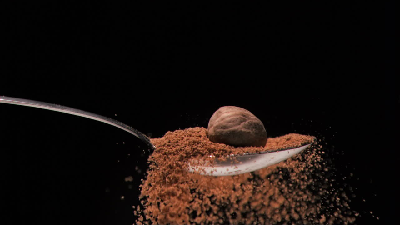 Brown nut falling in super slow motion in a spoon with powder