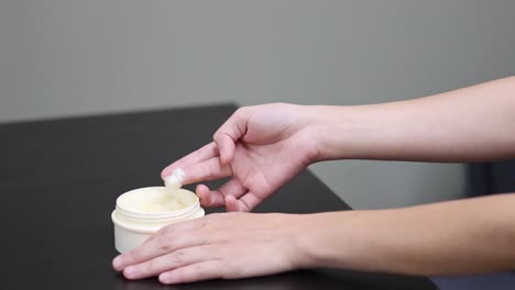 applying cream to hands from a jar