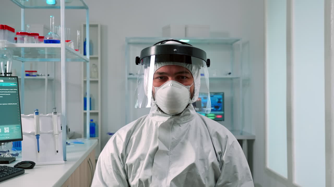 científico en traje de ppe mirando agotado a la cámara en el laboratorio