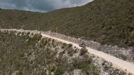 aerial view of jeep driving to the top of a mountain, off road driving uphill, tracking shot