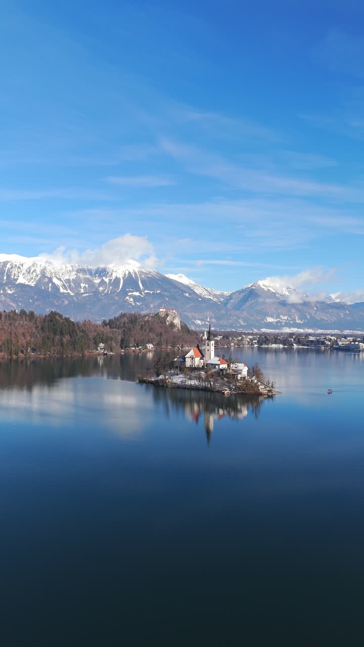 Vista aerea sul Lago di Bled con l'isolotto e la chiesa in inverno, le Alpi innevate sullo sfondo