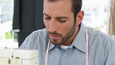 handsome fashion designer using sewing machine