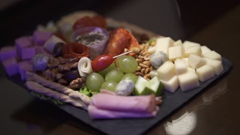 Una-Toma-Panorámica-De-Una-Variedad-De-Quesos-Y-Otros-Entrantes-Conforman-El-Elegante-Plato-De-Aperitivo,-Perfecto-Para-Cenas-De-Negocios-O-Cualquier-Evento-Especial.