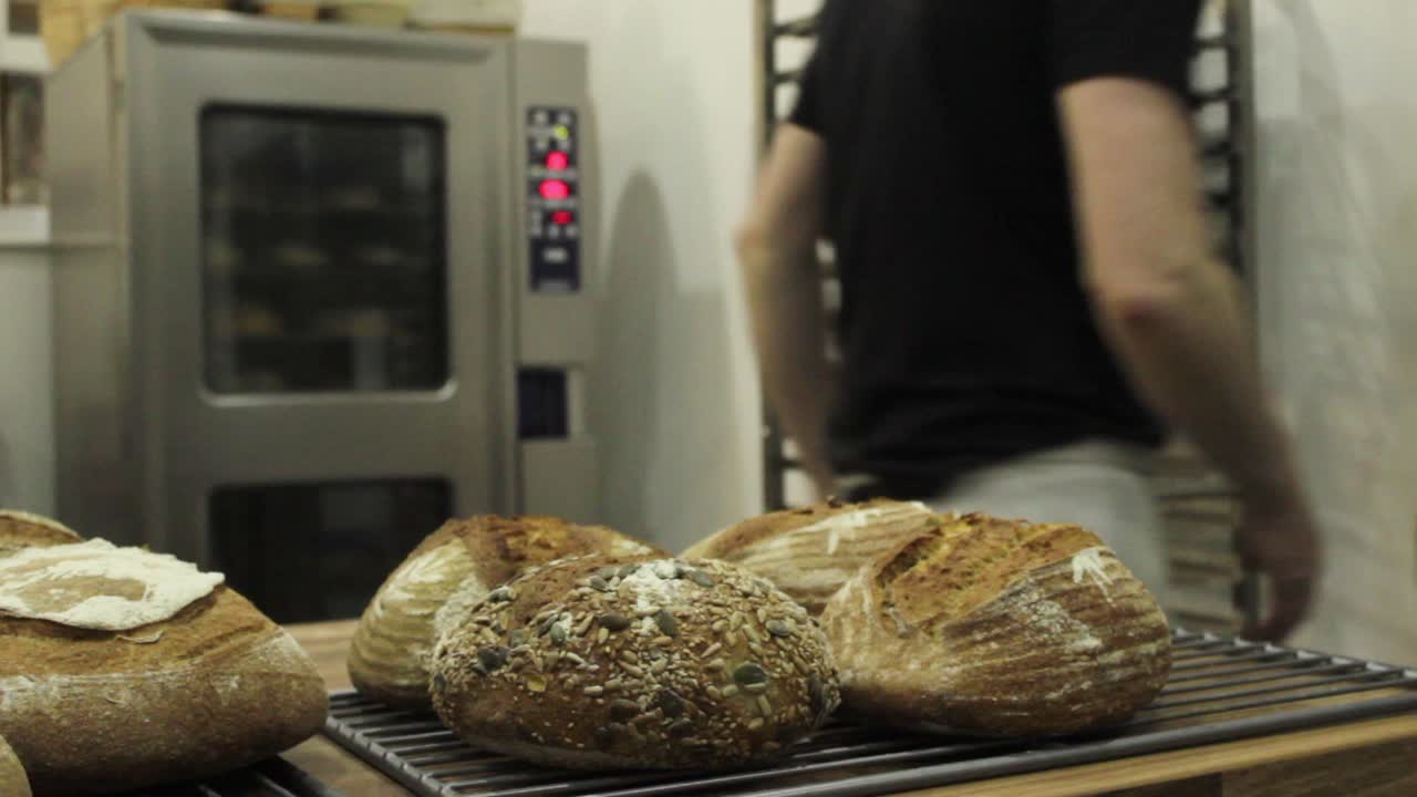 panadero masculino organizando pan para la venta en la tienda antes de abrir