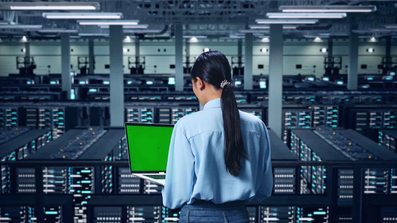 Back View Of Asian Business Woman Using Laptop Computer With Mock Up Green Screen In Data Center