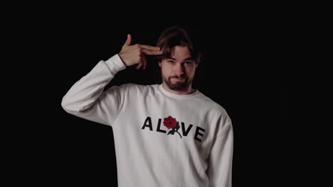 trendy young man shooting finger gun at head, wide, black background