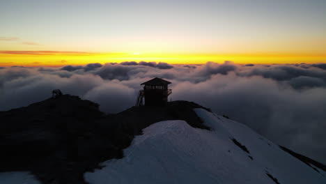 Flying-above-the-clouds-towards-the-sunset-with-a-revealing-view-of-the-mountain-summit-of-Mount-Rainier-volcano,-beauty-in-nature