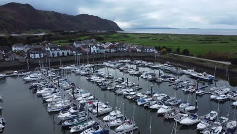 scenic luxurious waterfront harbour apartment village yachts and sailboats under mountain coastline aerial view flyover