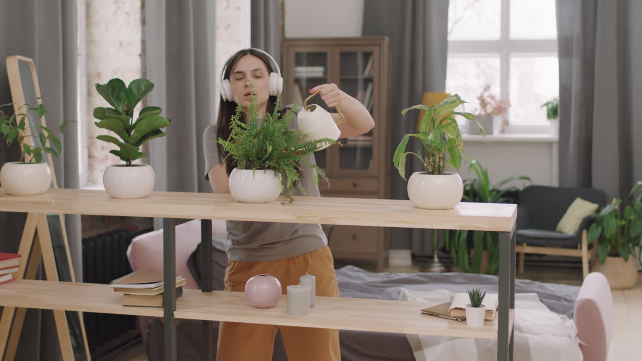 Woman Dancing to Music and Watering Plants