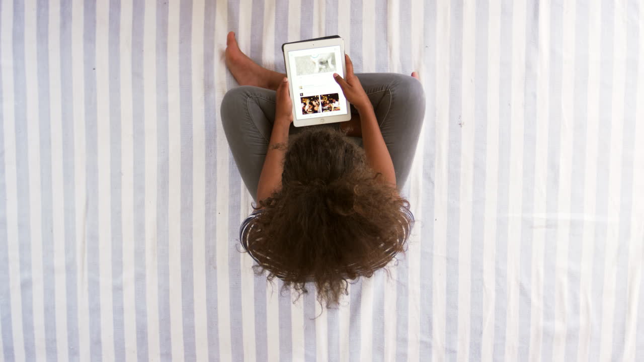 Vista dall'alto di una ragazza adolescente che guarda un tablet digitale sul letto
