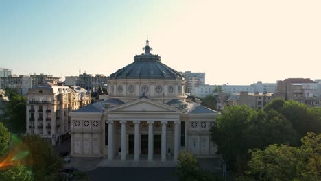 top down view over the romanian athenaeum at sunrise in bucharest surrounded by tall, historic buildings