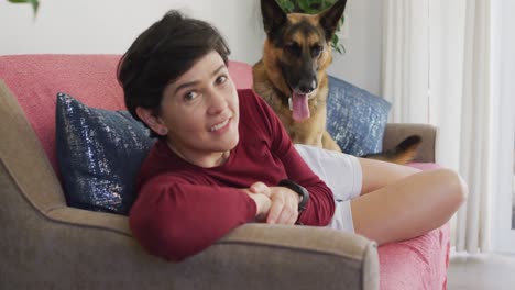 retrato de una mujer caucásica sonriendo acostada en el sofá con su perro en casa