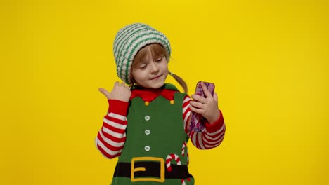 Kind,-Mädchen-Im-Weihnachtselfen-Weihnachtsmann-Helferkostüm,-Das-Einen-Videoanruf-Auf-Dem-Mobiltelefon-Tätigt