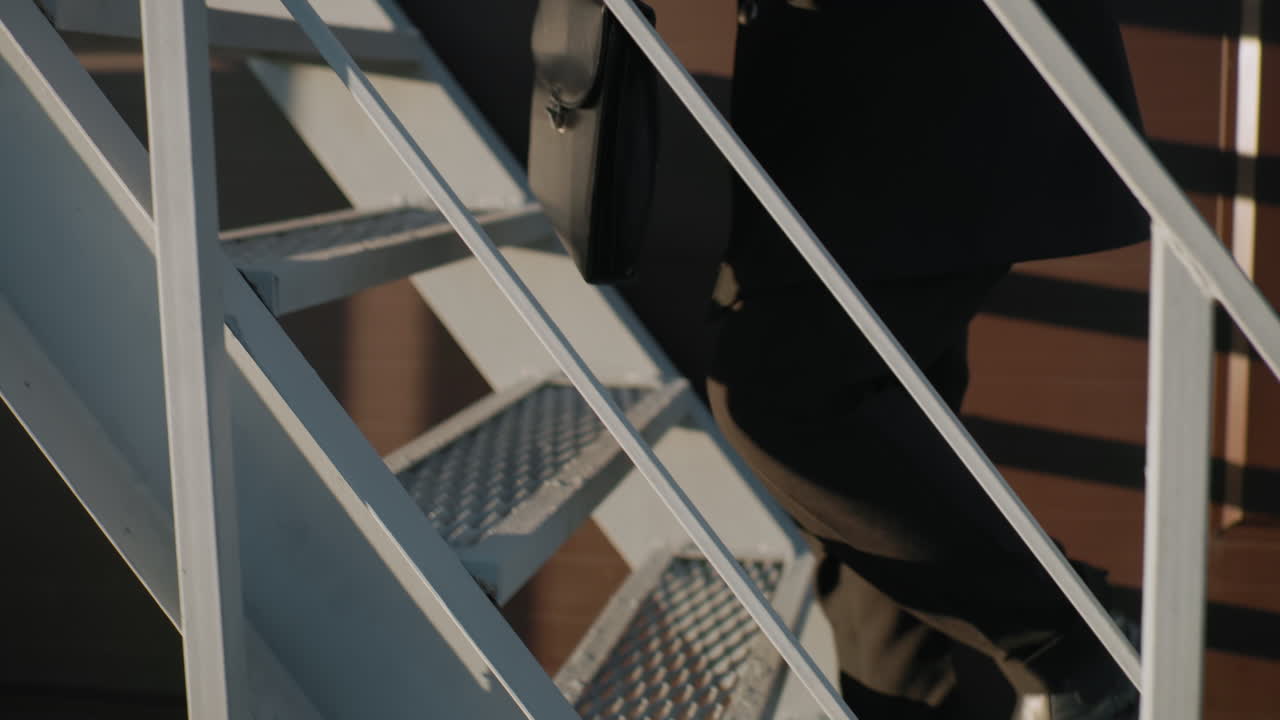 개인 등반 계단, 왼쪽 손에서 오른쪽 손으로 브리프케이스를 전환, 비즈니스 움직임, 적응력 및 전문 도시 환경에서 멀티 태스킹을 보여줍니다.