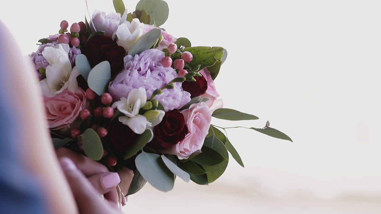 жених обнимает невесту, держа букет с разными цветами.