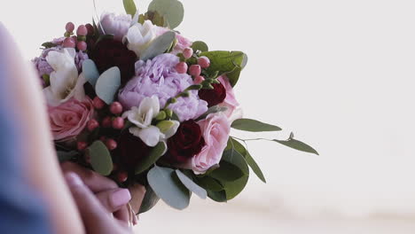 groom hugs bride holding bouquet with different flowers