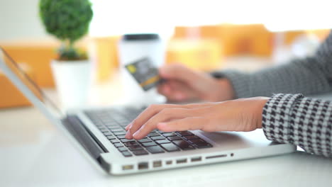 manos de mujer joven escribiendo en números de tarjeta de crédito de laptop, concepto de compras en línea, cerrar