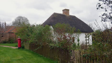 thatched cottage with a rustic fence and a classic british red post box, capturing rural england charm in a small village in the countryside