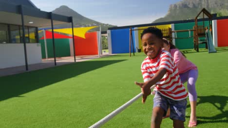 Front-view-of-mixed-race-schoolkids-playing-tug-of-war-in-the-school-playground-4k