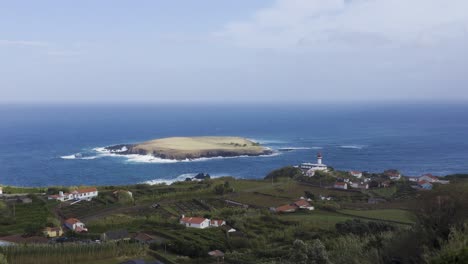 rural coastal village with a lighthouse and an island in the atlantic ocean, cloudy sky in topo, são jorge island, the azores, portugal