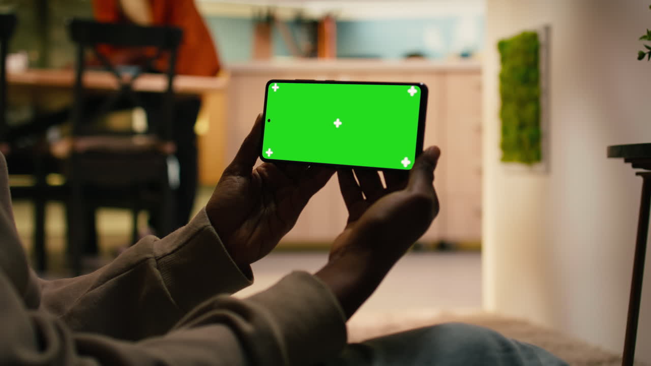 Primo piano di mockup con schermo verde e donna afroamericana in un interno accogliente.