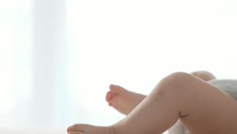 side view of mum's hands holding baby's legs