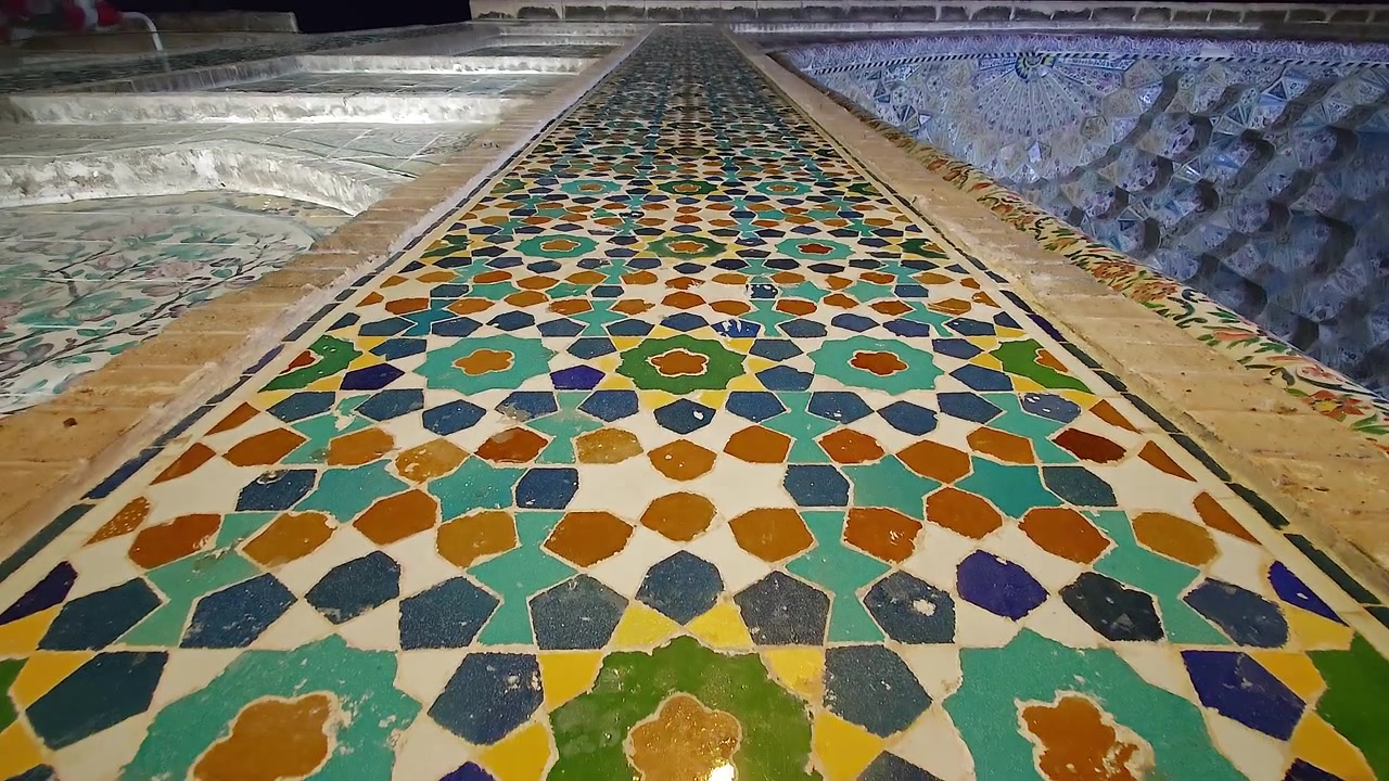 Intricati motivi geometrici di piastrelle su un'antica parete di moschea