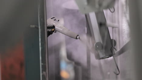 spraying powder paint on metal products with powder coating gun - close up
