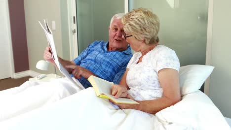 senior couple reading book and newspaper