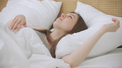 woman wakes up raise stretches hands in bed feels healthy