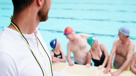 swim coach standing with whistle near poolside