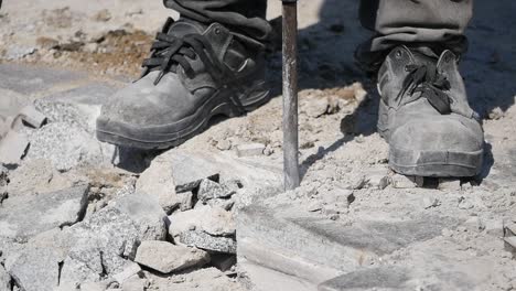 trabajador que usa un martillo para romper las piedras de pavimentación.