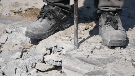 worker using a jackhammer to break up paving stones.