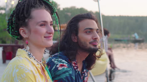 multiethnic couple smiling and chatting on lake pier