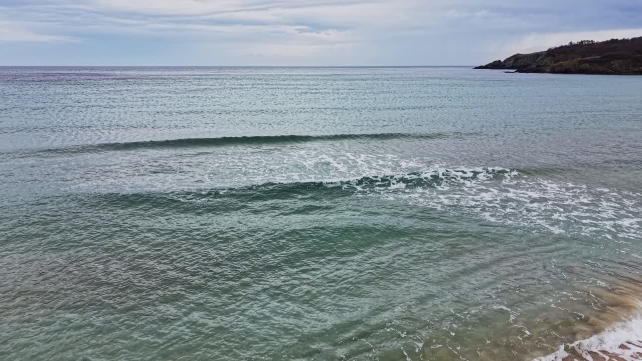 Onde si infrangono delicatamente sull'acqua cristallina vicino a una riva tranquilla nel pomeriggio