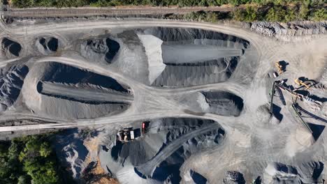 Top-down-aerial-of-large-piles-of-stones-and-rock-at-mining-facility