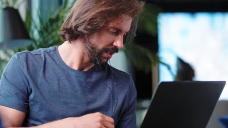 Young-adult-man-using-laptop-in-living-room