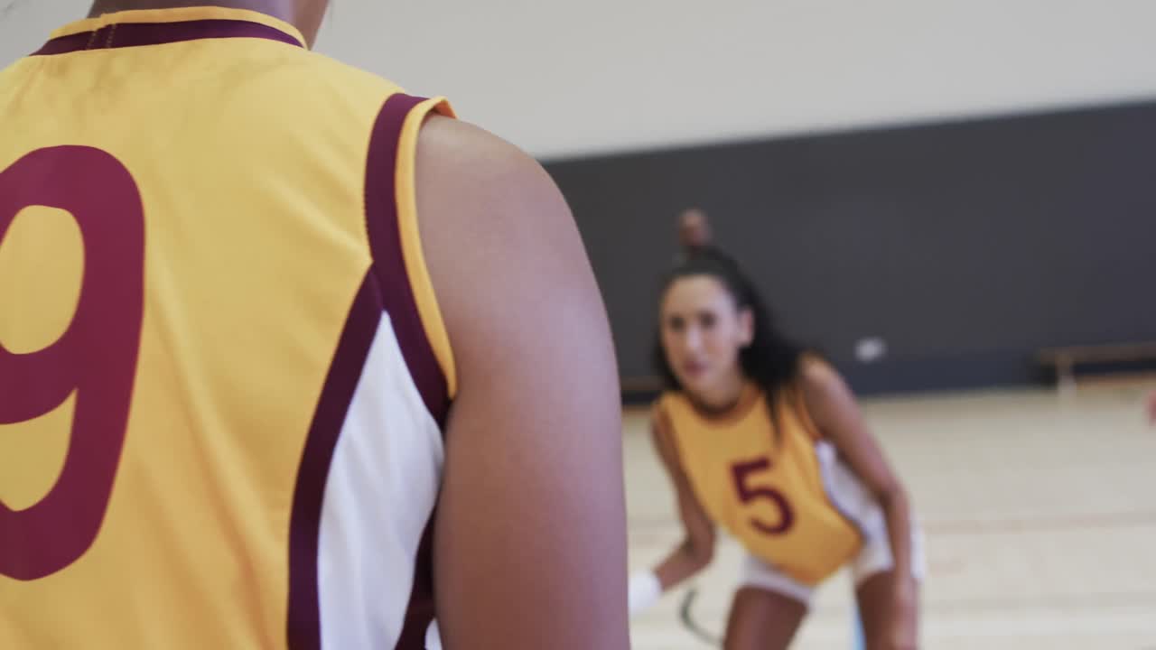 entrenamiento de un equipo de baloncesto femenino diverso con un entrenador masculino en una cancha cubierta, en cámara lenta