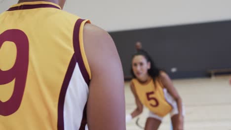 diverse female basketball team training with male coach in indoor court, in slow motion