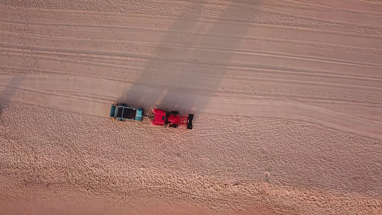 남자 다운 해변을 청소하는 해변 추적기의 공중 샷