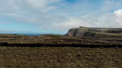 Girl-Standing-at-the-Edge-of-a-Cliff-Next-to-the-Sea-as-a-Drone-Fly's-By