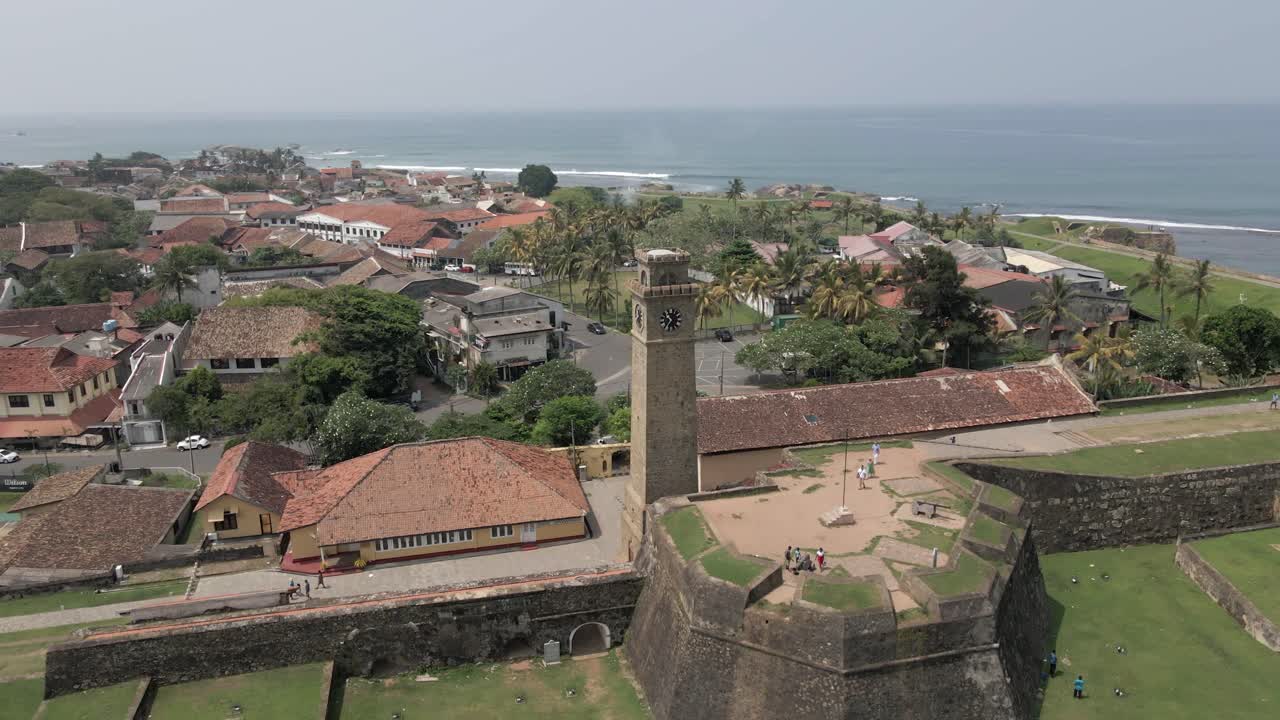 Luftaufnahme, die den Uhrturm und die steinernen Befestigungsanlagen des Galle Forts an der Küste umkreist
