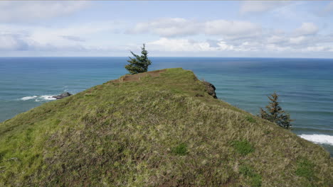 aerial view over green coastal hill top overlooking turquoise ocean at oregon coast, god's thumb region usa