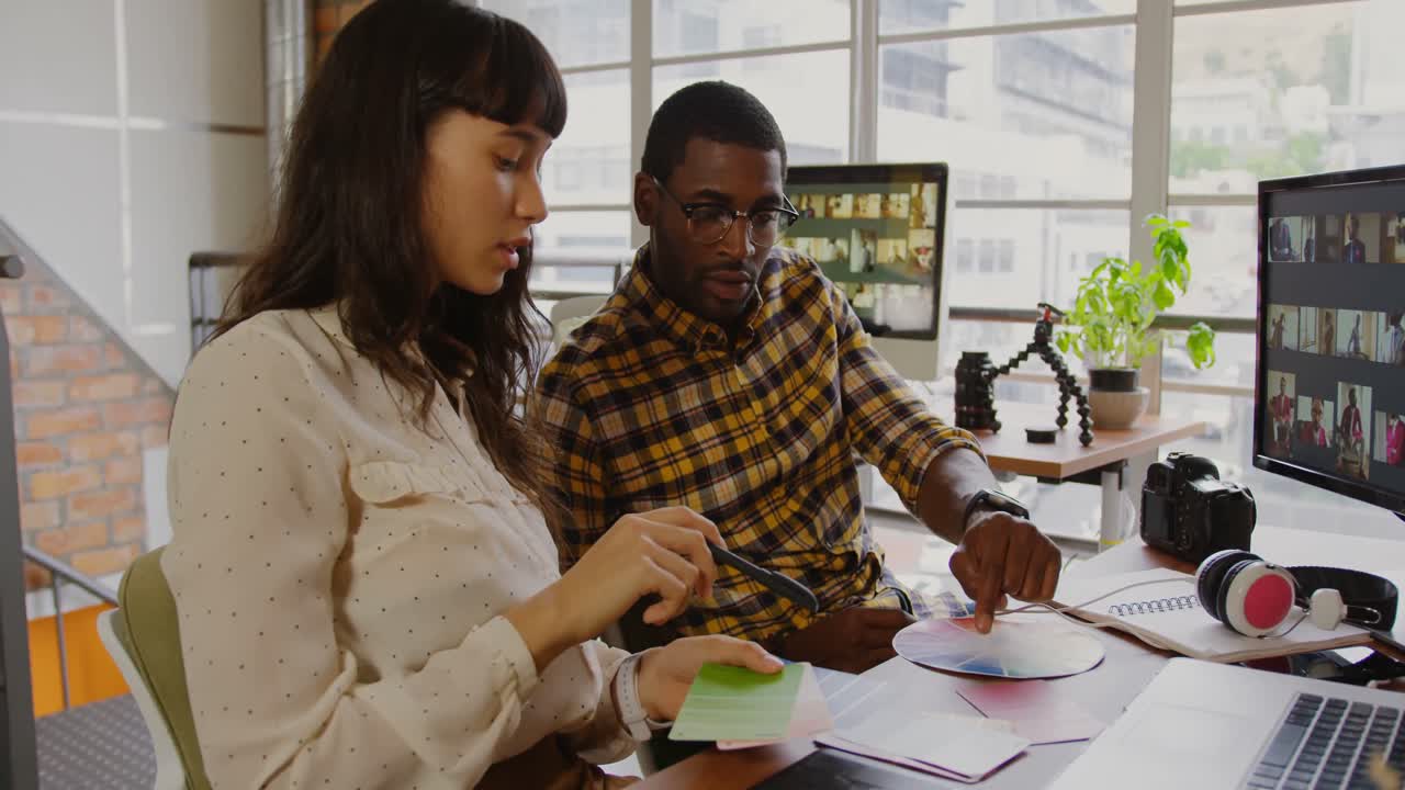 Graphic designers working together at desk in a modern office 4k