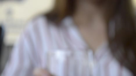 chica agarrando un vaso de agua fría y bebiéndolo, inclinándose hacia arriba saliendo de foco