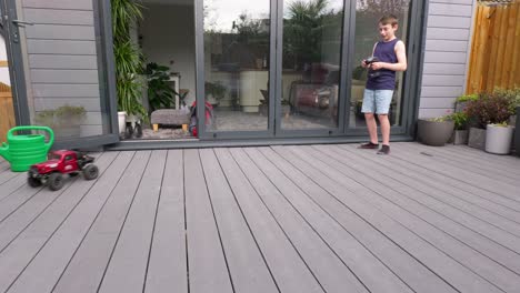 young boy at home outdoors in the garden playing with his rc car, truck, 4 x 4